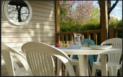 - une table et des chaises blanches sur une terrasse couverte dans l'établissement camping Le Clos de la Lère, à Cayriech