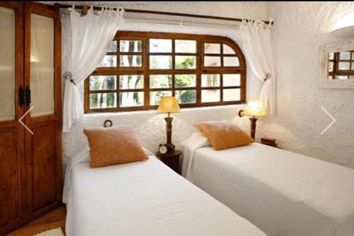 2 camas en una habitación con ventana en La Ginesta Rural, cerca de Sitges, en Canyelles