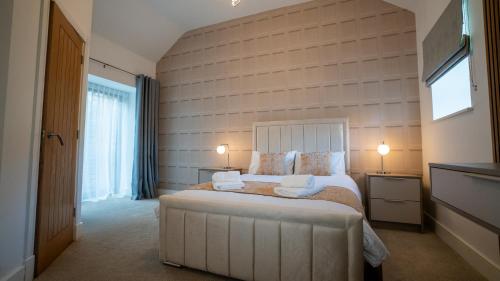 a bedroom with a large white bed with two lamps at Northumberland Luxury Stays - The Shearling in West Chevington