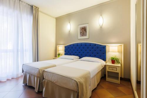 Hotel Le Mura في فولينيو: سريرين في غرفة الفندق مع اللوح الأمامي الأزرق