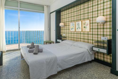 een slaapkamer met een groot bed en een groot raam bij Suitur apartamento frente a la playa de calafell in Calafell