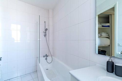 biała łazienka z prysznicem i umywalką w obiekcie Agréable appartement près de la capitale w mieście Neuilly-sur-Seine