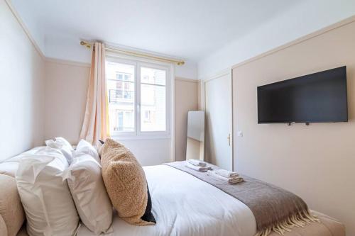 a bedroom with a bed with pillows and a flat screen tv at Agréable appartement près de la capitale in Neuilly-sur-Seine