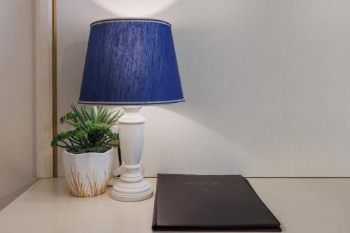 a blue lamp sitting on a table with a book at Hotel Le Mura in Foligno