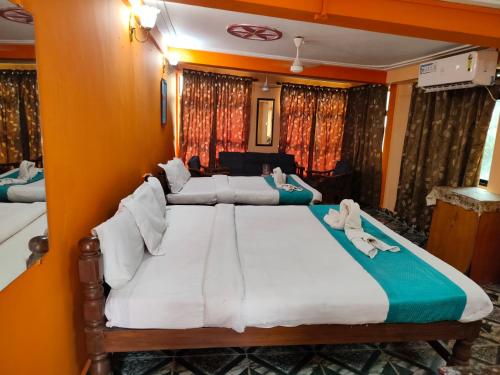 two beds in a room with orange walls and curtains at Neev Beach View Goa in Anjuna