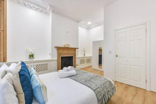 a white bedroom with a large bed and a fireplace at 2 Bed Piccadilly Apartment- 2 in London
