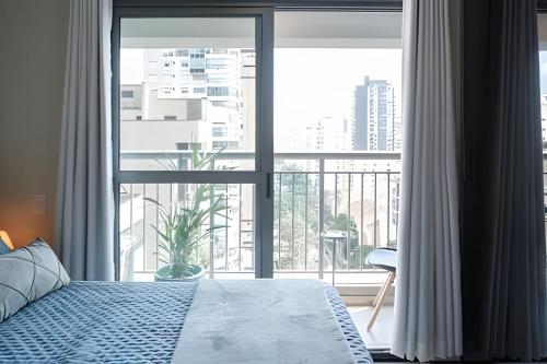 a bedroom with a bed and a large window at Studio 1305 Id Jauaperi in Sao Paulo