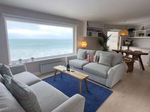 a living room with two couches and a large window at Aggie Beach Apartment - Unrivalled Beach Views in St. Agnes