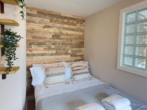 a bedroom with a wooden accent wall and a bed at Aggie Beach Apartment - Unrivalled Beach Views in St. Agnes