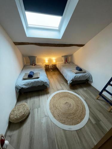 Habitación con 2 camas y alfombra en el suelo en Le grenier de Charlotte, en Libin