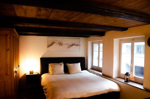 a bedroom with a large white bed with two windows at MANY'S historical city central APARTMENTS in Zürich