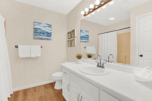 a white bathroom with a sink and a toilet at North Tybee Beach Home, Near the Beach, Restaurants, Shops and More! Heated Pool Access in Tybee Island