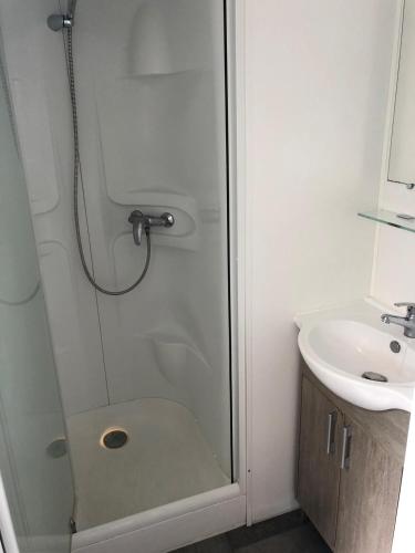 une douche avec une porte vitrée à côté d'un lavabo dans l'établissement Mobile-home les pieds dans l'eau, à Palavas-les-Flots