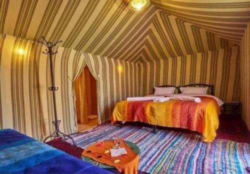 Cette chambre comprend 2 lits et une table. dans l'établissement Desert Berber Fire-Camp, à Merzouga