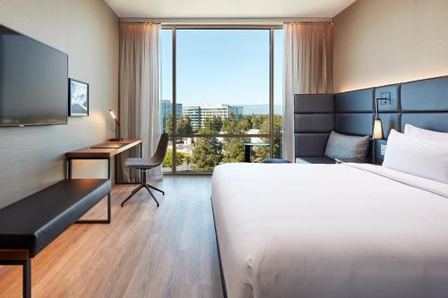 a hotel room with a bed and a desk and a window at AC Hotel by Marriott San Jose Santa Clara in Santa Clara