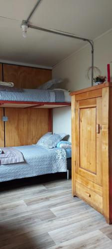 a bedroom with two bunk beds and a wooden cabinet at CABAÑA EL BUHO - ESMERALDA in Puerto Natales