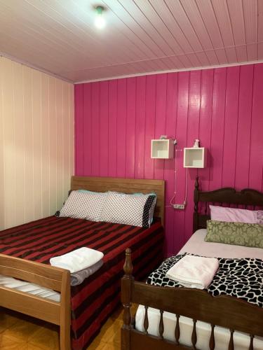2 camas en una habitación con paredes rosas en Orange House Canela, en Canela