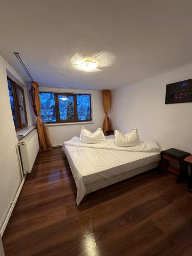 sypialnia z łóżkiem z białą pościelą i drewnianą podłogą w obiekcie Pensiunea Stefan w mieście Durău