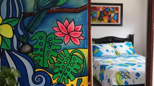 a bedroom with a bed and a colorful painting at Hostal Palmas De Cocora in Salento