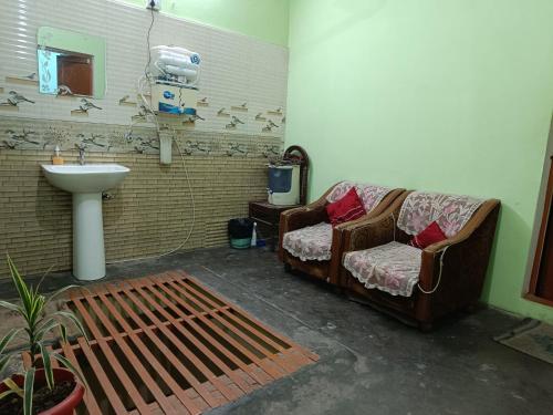 uma casa de banho com um sofá e um lavatório num quarto em JPM Hostel em Varanasi
