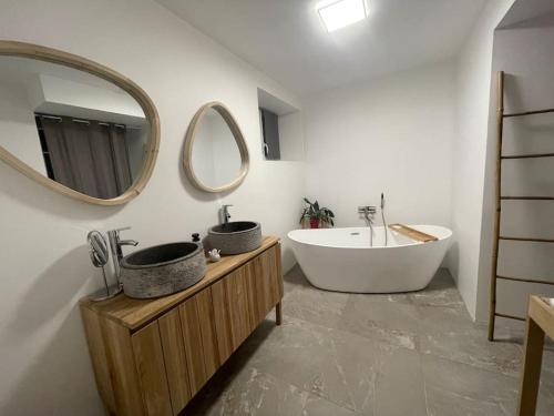 een badkamer met 2 wastafels, een bad en een spiegel bij La Pelencas - Maison individuelle - clim - WIFI in Arthès