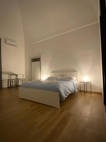 a white bedroom with a bed and two tables at Le Stanze Di Ambra in Trani