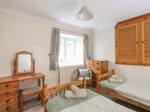 a bedroom with two beds and a mirror and a dresser at Glan Gors in Llandyfrydog
