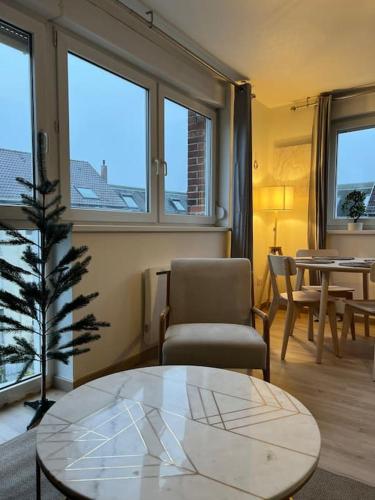 - un salon avec une table, une chaise et des fenêtres dans l'établissement Adorable Appartement Strasbourg NEUDORF PARKING SOUS SOL, à Strasbourg