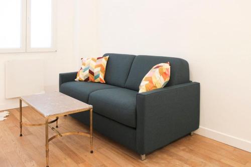 un canapé bleu dans un salon avec une table dans l'établissement Nice 30 m near Canal St Martin, à Paris