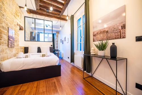 une chambre avec un lit blanc et un mur de briques dans l'établissement Lovely apartment in Paris -, à Paris