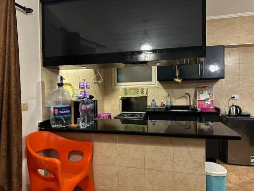 a kitchen with a black counter and a orange chair at Telal elsokhna families in Ain Sokhna