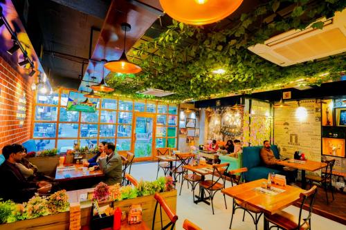 ein Restaurant mit Tischen und Personen, die an Tischen sitzen in der Unterkunft Hotel Pinkcity Prime & Chicago View Cafe in Jaipur