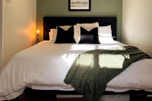 um quarto com uma grande cama branca com almofadas pretas em Chic, Relaxing stay just 18 mins into the City em Londres