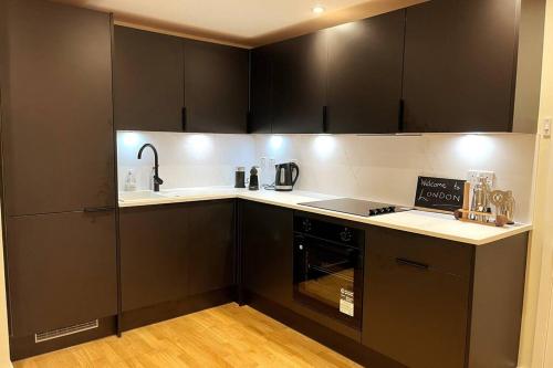 a kitchen with black cabinets and a counter top at Chic, Relaxing stay just 18 mins into the City in London