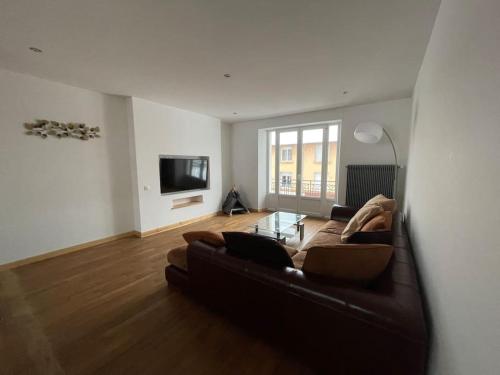 un salon avec un canapé brun et une télévision dans l'établissement Appartement lumineux avec balcon, à Gérardmer