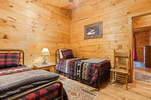 Dormitorio en cabaña de madera con 2 camas y una silla en Hillside Haven, en Blue Ridge