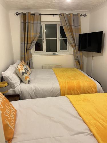 a room with two beds and a tv and a window at Princess Wigan House in Wigan