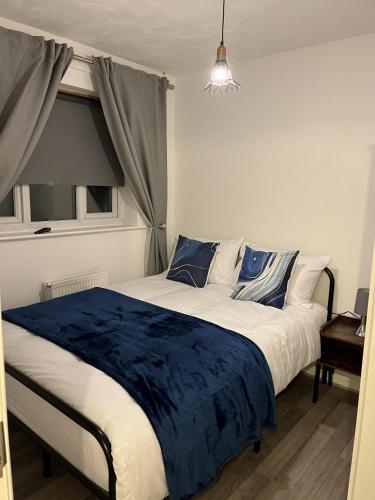 a bedroom with a large bed with blue sheets and a window at Princess Wigan House in Wigan