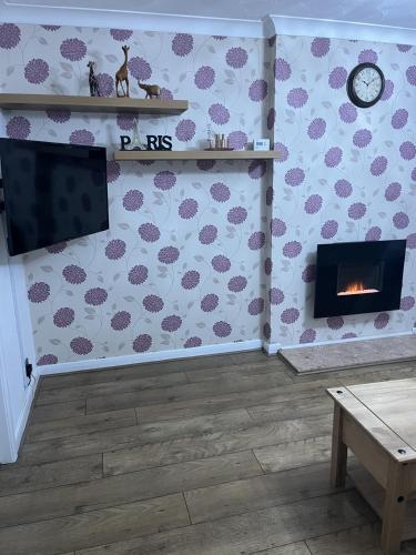a living room with a fireplace and a tv at Princess Wigan House in Wigan