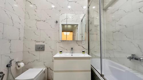 uma casa de banho com um lavatório, uma banheira e um espelho. em Azure Residence em Baku