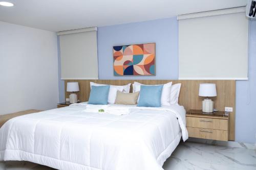 a bedroom with a large white bed with blue accents at Habana Hotel Y Restaurante in Higuey