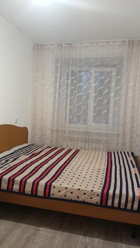 Bett in einem Zimmer mit Fenster in der Unterkunft 3-х комнатная квартира в Павлодаре in Pawlodar