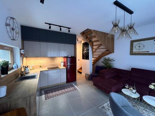 a kitchen and a living room with a red couch at Villa Monte Apartament z ogrodem in Kudowa-Zdrój