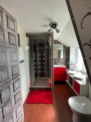 une salle de bain avec douche et un tapis rouge dans l'établissement La Maison d'Andrée, à Pluvet
