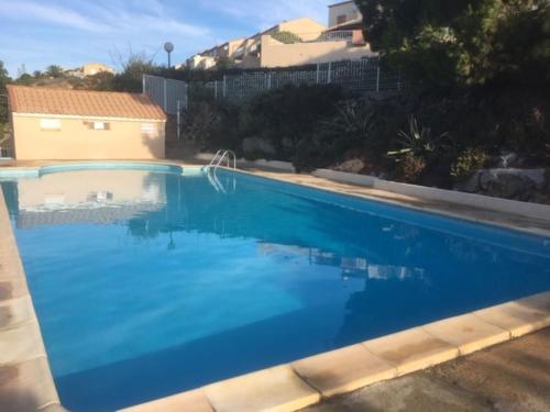 une grande piscine avec de l'eau bleue dans l'établissement Arc en ciel, vue mer et piscine dans résidence, à Saint Pierre La Mer