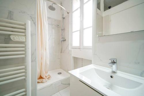 une salle de bain blanche avec un lavabo et une douche dans l'établissement Studio Buttes-Chaumont - Hautpoul - IV, à Paris