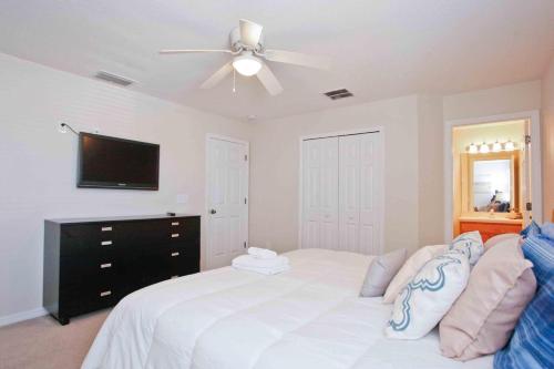 1 dormitorio con 1 cama blanca y ventilador de techo en 4 Bedroom Vacation Homes Bella Vida Resort en Kissimmee