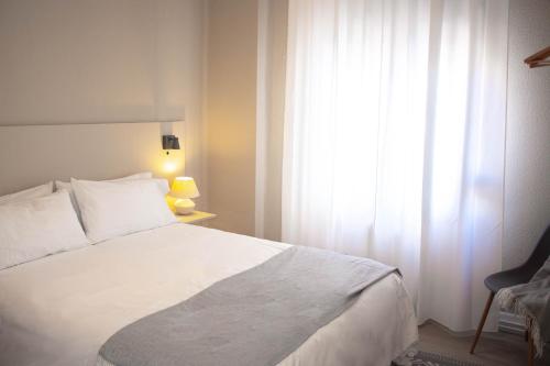 1 dormitorio con cama blanca y ventana en Apartamentos Albacete, en Albacete