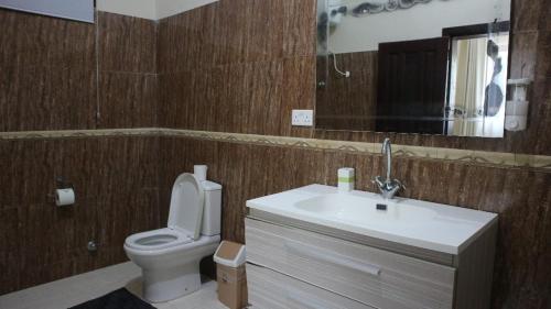 a bathroom with a toilet and a sink and a mirror at Cliffhaven Beach Resort Hotel in Accra