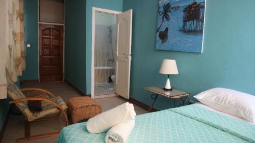 a bedroom with blue walls and a bed and a chair at Cliffhaven Beach Resort Hotel in Accra